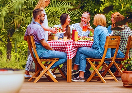 Group of friends eating grilled food during meeting in the yard