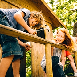 Friends who are children working together to build a treehouse, hammering, helping and sawing on a summer day