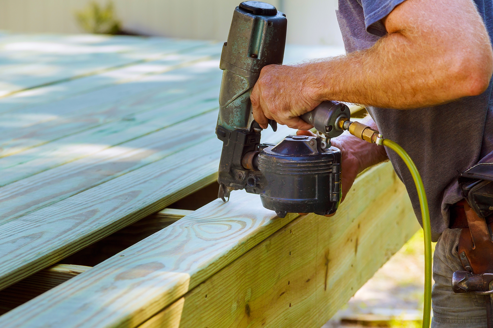 Installing Wood on deck, patio construction man using pneumatic nailer air gun